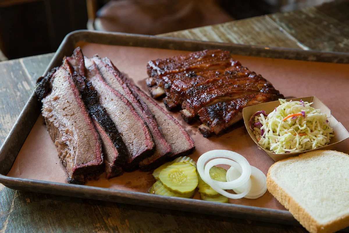 Sliced smoked brisket, ribs, slaw and pickles on a barbecue tray